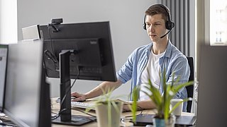 Unser Kollege sitzt am Arbeitsplatz und blickt auf den Monitor